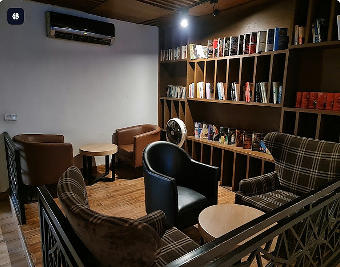 Seating area with tartan armchairs and a book wall inside Second Cup Johar Town
