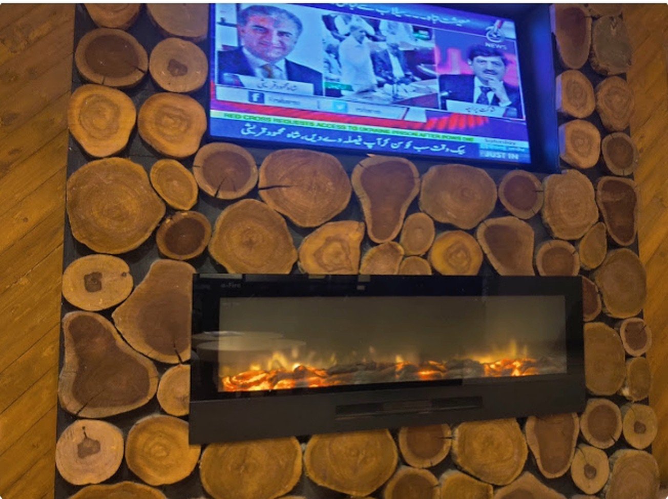 Electric fireplace set into a log-slice feature wall at Second Cup Johar Town