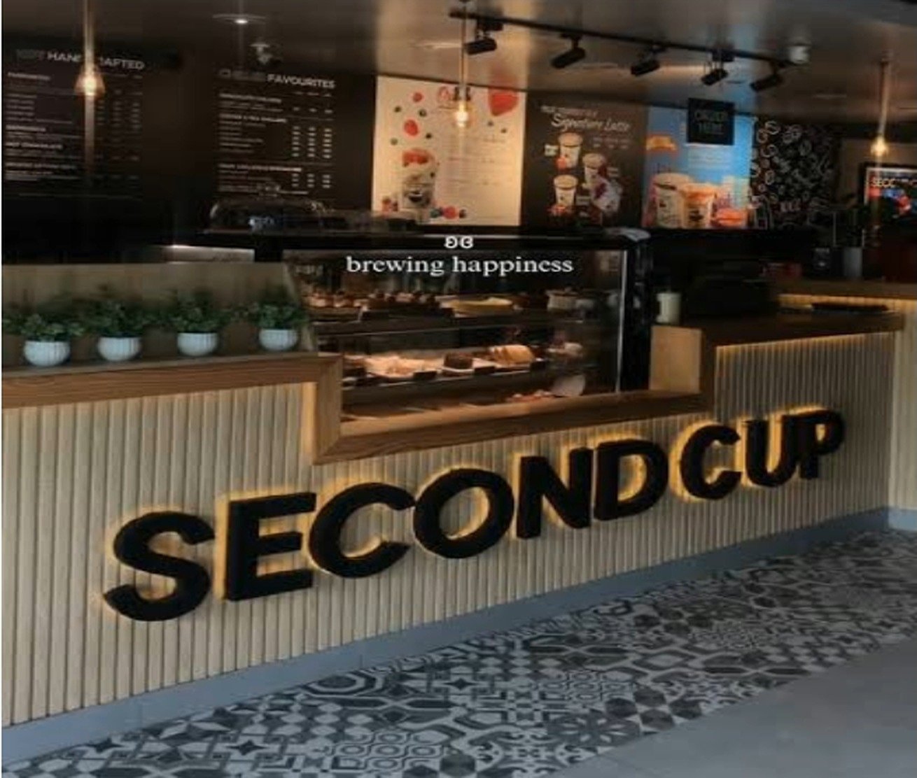 Illuminated SECOND CUP signage above the counter and pastry case in Johar Town